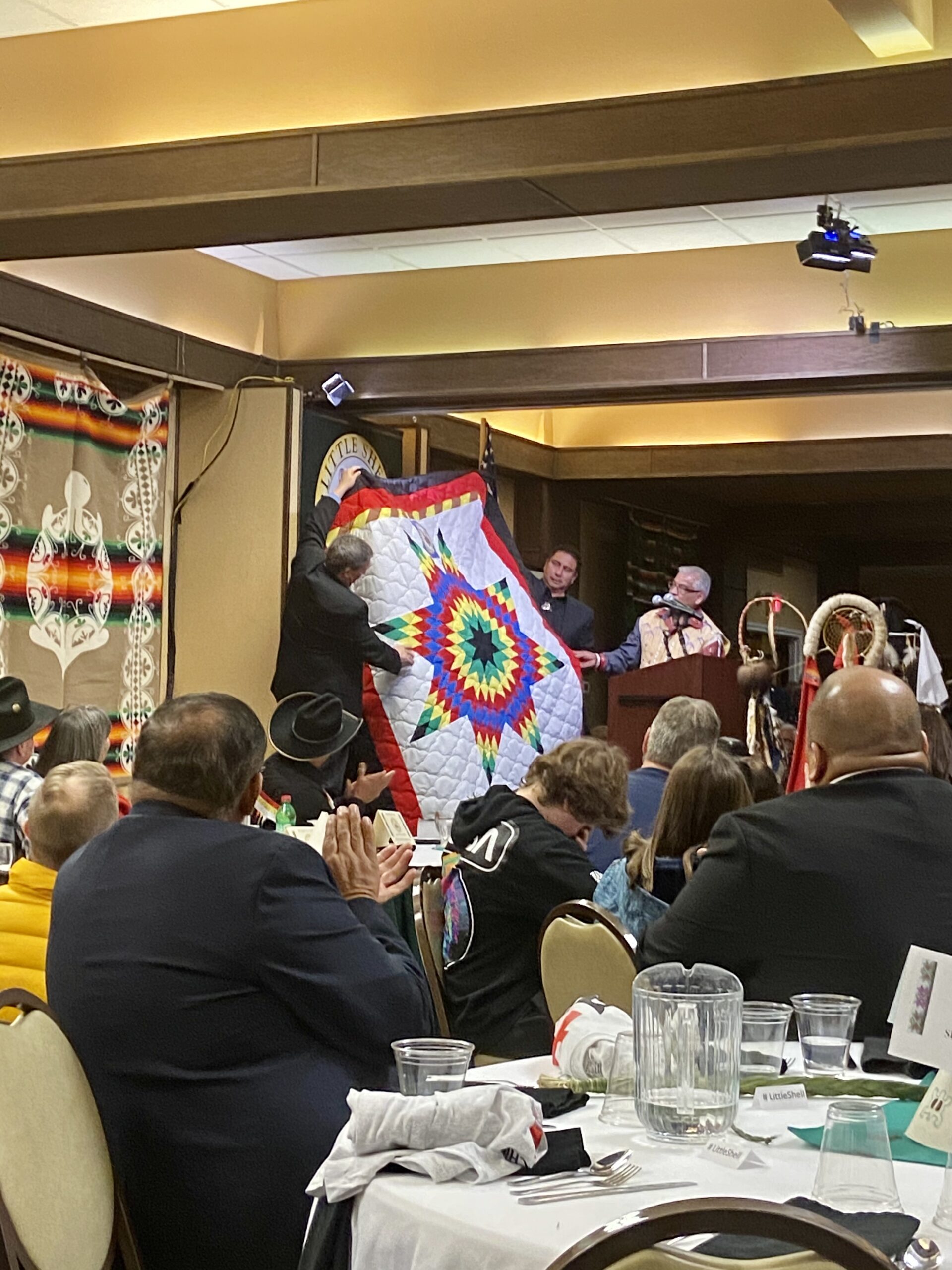 Former Turtle Mountain Chairman Merle St.Claire gifting a star blanket in honor of Little Shell federal recognition. Photo Courtesy of Katherine McCleary﻿